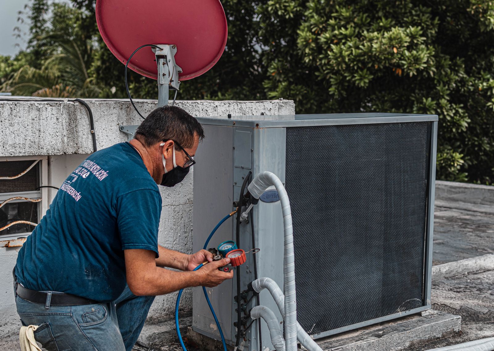 Technician checking hose connections on an outdoor air-conditioning unit