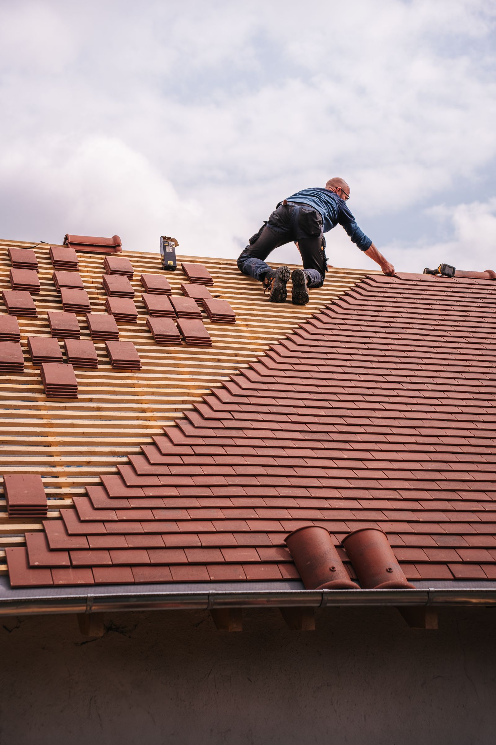 Roofer installing shingles on a new home